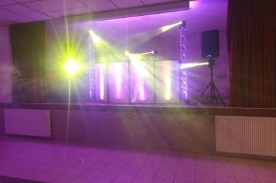 Installation de matériel de sonorisation et éclairage avec projecteurs colorés sur une scène dans une salle.