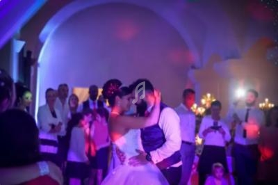 Un couple danse lors de leur mariage, entouré d'invités sous des lumières colorées dans une salle festive.