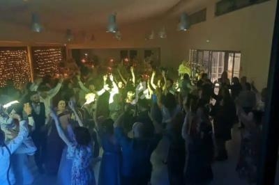 Groupe de personnes dansant dans une salle éclairée, décorée de guirlandes lumineuses et de tables festives.