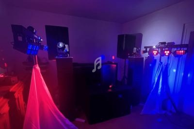 Équipement d'éclairage et de sonorisation dans une pièce sombre, illuminée par des lumières rouges et bleues.