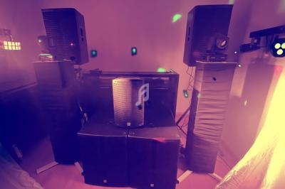 Ensemble de haut-parleurs et équipements audio installés dans une pièce avec éclairages colorés diffus.