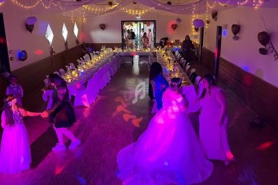 Salle de réception décorée avec des guirlandes lumineuses, des invités dansent et discutent autour de tables dressées.