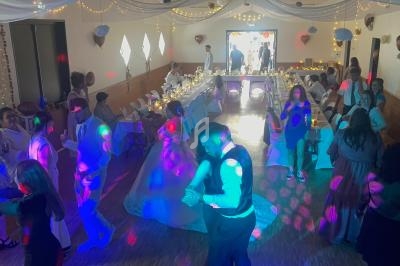 Des invités dansent et discutent dans une salle décorée pour une réception avec tables dressées et éclairages festifs.