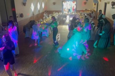 Des invités dansent dans une salle décorée, éclairée par des lumières colorées, lors d'une réception festive.