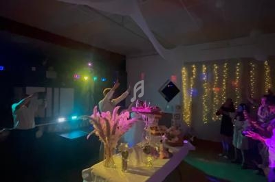 Salle faiblement éclairée avec des invités autour d'une table décorée, éclairages colorés et guirlandes lumineuses en…