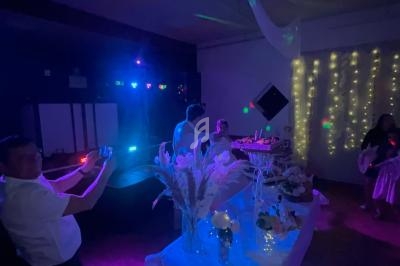 Salle faiblement éclairée avec des décorations lumineuses, une table ornée de fleurs et des invités en arrière-plan.