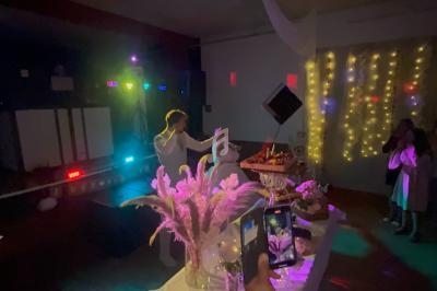 Un couple danse sous des lumières colorées lors d'une fête, avec une table décorée au premier plan.