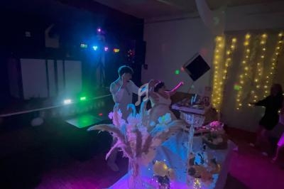 Un couple danse dans une salle faiblement éclairée, décorée de guirlandes lumineuses et de fleurs.