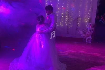 Un couple danse sous des lumières colorées dans une ambiance festive avec un décor illuminé en arrière-plan.