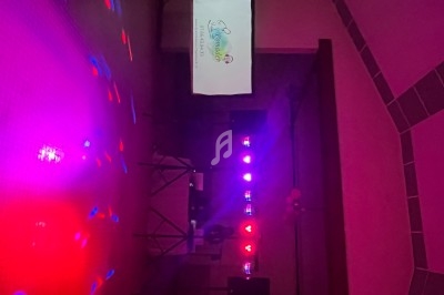 Éclairage coloré et écran de projection dans une salle sombre, ambiance festive ou événementielle.