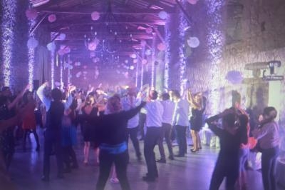 Groupe de personnes dans une salle en pierre éclairée, dansant sous des décorations suspendues.