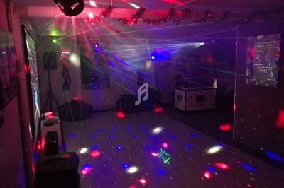 Salle sombre avec des jeux de lumière colorés, lasers et spots projetés sur les murs et le sol.