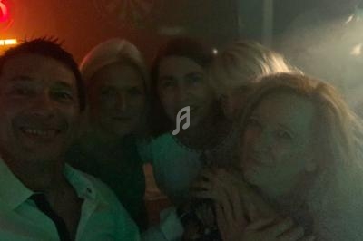 Un groupe de personnes souriant dans un environnement sombre avec des lumières tamisées en arrière-plan.