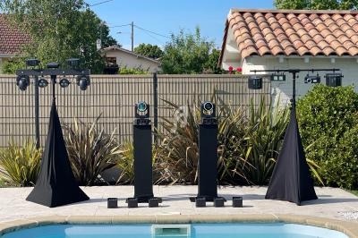 Équipement d'éclairage installé près d'une piscine, entouré de végétation et de maisons en arrière-plan.