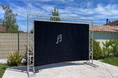 Structure métallique avec un grand panneau noir tendu, installée sur une terrasse en extérieur par temps ensoleillé.