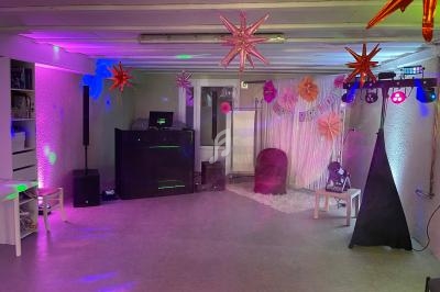 Salle décorée pour une fête d'anniversaire avec guirlandes, lumières colorées et équipement de sonorisation.