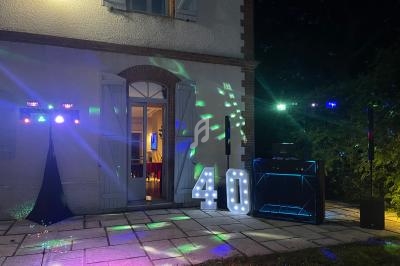 Façade de maison éclairée la nuit avec décorations lumineuses, chiffre ’40’ illuminé et équipements de fête.