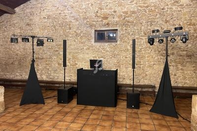Installation de matériel de sonorisation et d'éclairage dans une salle aux murs en pierre et au sol en carrelage.