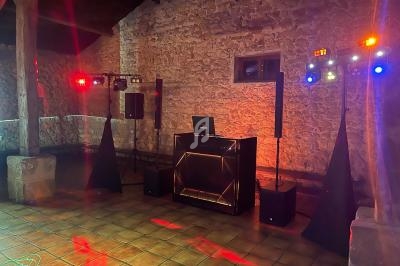 Installation de matériel de sonorisation et éclairage coloré dans une salle en pierre avec sol carrelé.