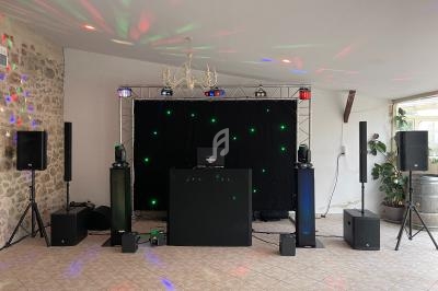 Installation de matériel de sonorisation et d'éclairage pour un événement dans une salle avec murs en pierre.