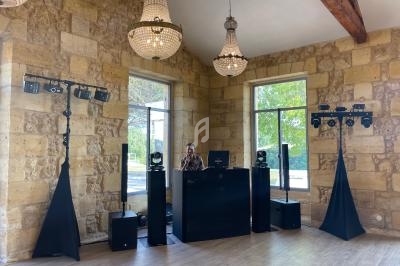 Un DJ mixe derrière une table noire dans une salle en pierre avec des lustres et des équipements d'éclairage.