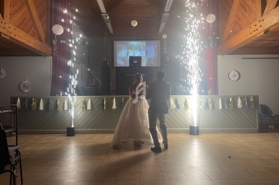 Un couple danse au centre d'une salle décorée, éclairée par des étincelles et des lumières festives.