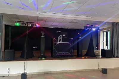 Équipement de sonorisation et éclairage installé sur une scène dans une salle avec des jeux de lumière colorés.