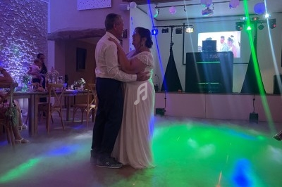 Un couple danse dans une salle de réception décorée, éclairée par des lumières colorées.