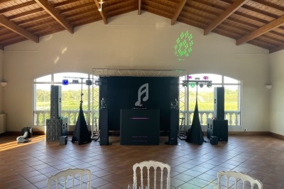 Salle de réception lumineuse avec équipement de sonorisation et éclairage, vue sur des vignobles à travers de grandes…
