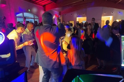 Personnes dansant et s'amusant lors d'une fête en intérieur, éclairée par des lumières colorées.