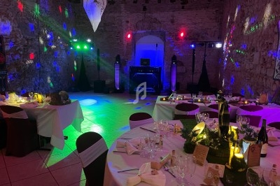 Salle de réception décorée avec des tables dressées, éclairages colorés et une piste de danse.