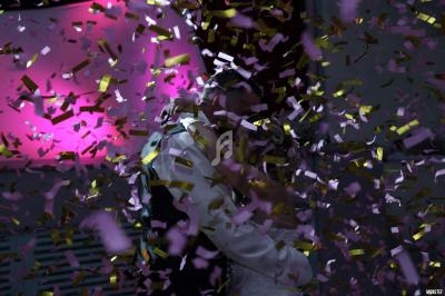 Un couple danse sous une pluie de confettis dorés et roses dans une ambiance lumineuse rose.