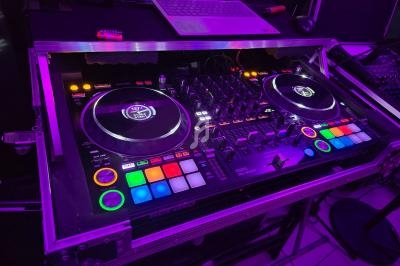 Table de mixage DJ avec platines, boutons colorés et ordinateur portable en arrière-plan dans un environnement éclairé en…