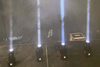 Quatre projecteurs émettant des faisceaux lumineux verticaux dans une ambiance enfumée, avec une boîte au sol.