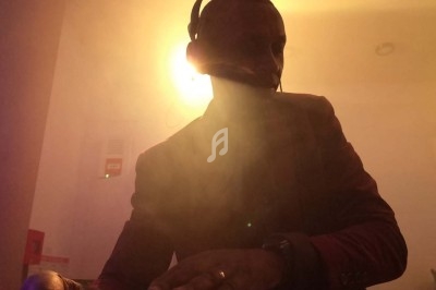 Un homme portant un casque-micro, éclairé par une lumière vive dans une ambiance enfumée.