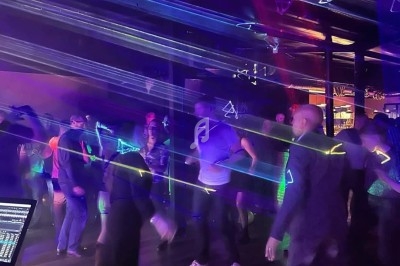 Personnes dansant dans une ambiance sombre avec des lumières laser colorées traversant la salle.