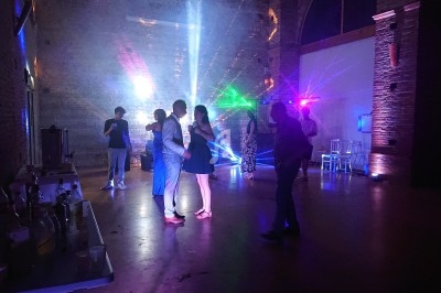 Personnes dansant et discutant dans une salle faiblement éclairée avec des jeux de lumière colorés.