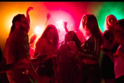 Personnes dansant dans une ambiance festive avec éclairages colorés rouge, jaune et vert.