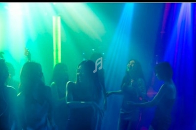 Des personnes dansent sous des lumières colorées dans une ambiance festive et tamisée.