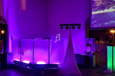 Installation d'éclairage violet et vert avec un écran projetant une image de plage dans une salle sombre.