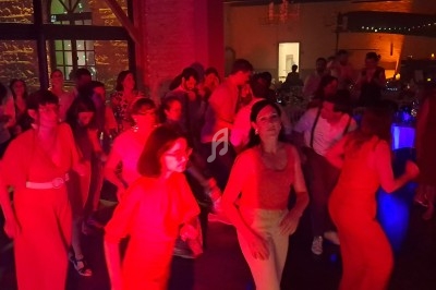 Des personnes dansent dans une salle éclairée par des lumières rouges et tamisées, ambiance festive.