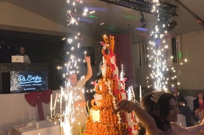 Un gâteau de mariage décoré de feux d'artifice entouré d'invités dans une salle de réception festive.