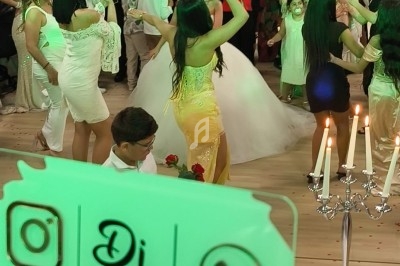 Des personnes dansent lors d'une fête animée, avec une pancarte de DJ visible au premier plan.