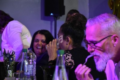 Des personnes assises à une table, discutant et partageant un moment convivial dans un environnement intérieur.