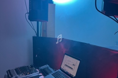 Poste de DJ avec platines, table de mixage et ordinateur portable, éclairé par des lumières bleues et rouges dans une…