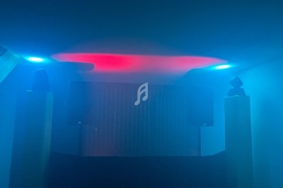 Deux colonnes éclairées en bleu encadrent une scène avec des lumières rouges et bleues dans une ambiance brumeuse.