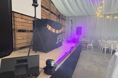 Scène décorée avec éclairage violet, écran de projection et enceintes dans une salle avec plafond drapé.