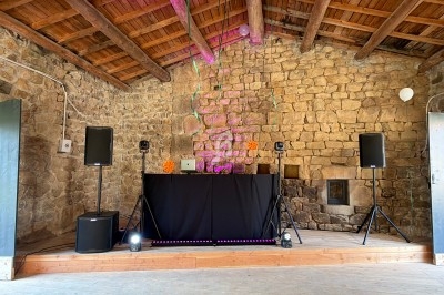 Installation de matériel de sonorisation et d'éclairage dans une salle en pierre avec plafond en bois.