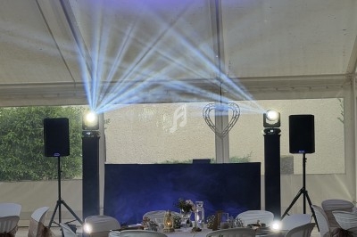Salle de réception décorée avec des tables dressées et éclairage lumineux projetant des faisceaux bleus.