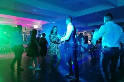 Des personnes dansent dans une salle éclairée par des lumières colorées, créant une ambiance festive.